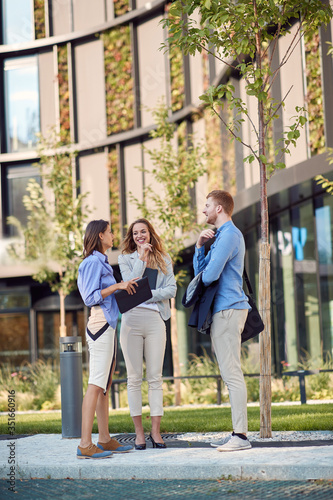 group of three caucasian business people talking in front of a building. spontaneous chat