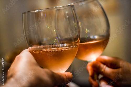 Hands and glasses of toasting friends with rose champagne close up