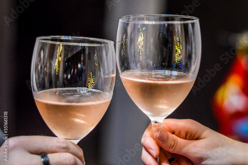 Hands and glasses of toasting friends with rose champagne close up