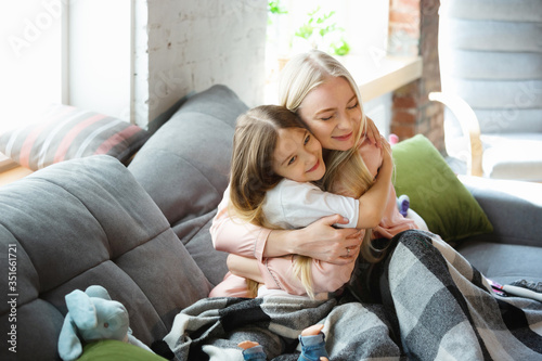 Mother and daughter, sisters have quite, beauty and fun day together at home. Comfort and togetherness. Concept of childhood, happiness, family's weekend, friendship, pajamas party. Domestic lifestyle photo