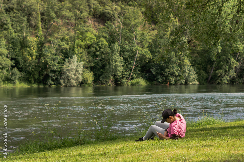 woman using mobile phone on river bank complete social isolation woman using mobile phone on river bank complete social isolation