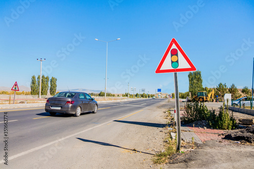 International warning traffic sign 'Traffic light regulation'. Some cars moving on highway