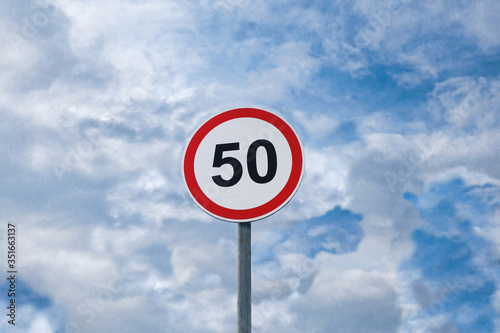 International traffic sign 'Speed limit' (to 50 km or miles per hour). Cloudy blue sky is on  background