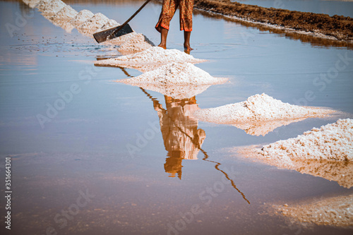 Vászonkép Cinematic photo of saltfield worker harvesting salt in Kampot Province in Cambod