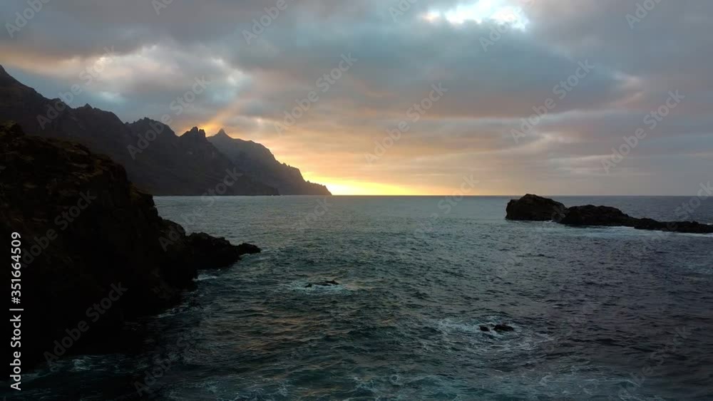 Morning sunrise dusk. Sea waves, hectic ocean. Drone aerial footage, waves crashing over rocks. Sun raising on horizon, behind hills on the background Morning sunrise dusk. Sea waves, hectic ocean. Drone aerial footage, waves crashing over rocks. Sun raising on horizon, behind hills on the background