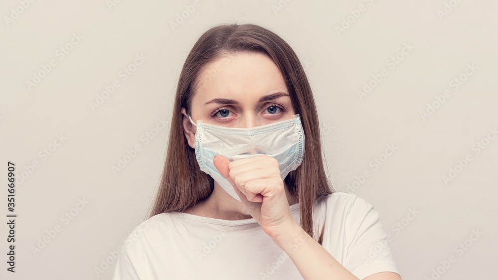 Girl in a medical mask is ill, girl coughing, white background, copy space, 16:9