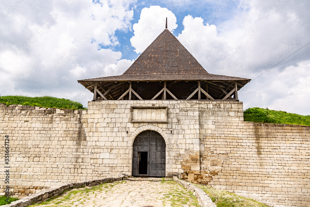 Gate of Khotyn Fortress castle in Ukraine on a background of dark clouds on a cloudy windy day in summer. Horizontal orientation.