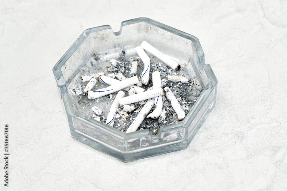 Fototapeta premium Ashtray with cigarette butts on a gray background