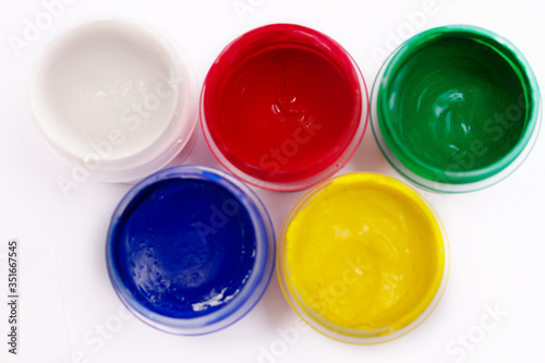 Cans of different colors gouache paints, top view, closeup, white background