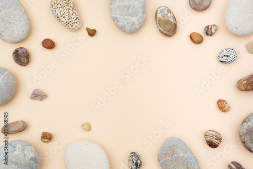 Mix of rounded multicolor textured stones on beige paper background . Flat lay with copy space