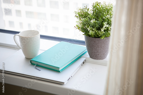  white mug  blue diary and notebook. light working morning