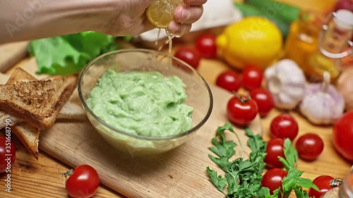 Closeup Of Hand Squeezes Lemon On Toast With Avocado. View of a table with a variety of fresh food on the table. Cooking a delicious healthy vegetarian breakfast  in slow motion. Healthy eating.