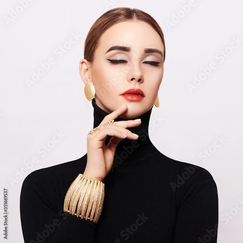 Art portrait of a beautiful, elegant woman in a black turtleneck and gold jewelry