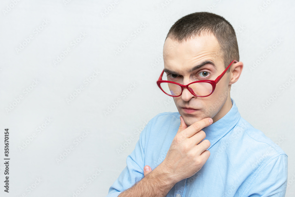 Nerd man with glasses thoughtfully looks at the camera and doubts something, portrait, white background, copy space Nerd man with glasses thoughtfully looks at the camera and doubts something, portrait, white background, copy space