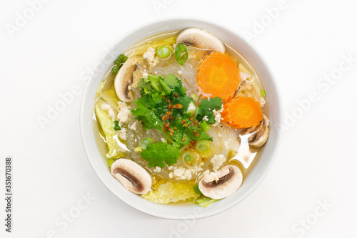 Gang Jued Woonsen is a Thai glass or bean thread noodle soup with small meatball served in white bowl on white background. photo