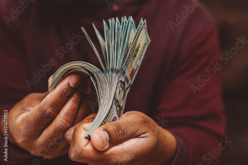 african american man with a stack of US one hundred dollar bills in his hands