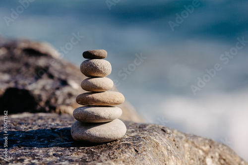Stones pyramid on pebble beach, stability, zen, harmony, balance concept. With blur sea background on a sunny day.