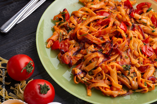  italian pasta with tomatos and herbs on dark wooden table. italian pasta recipe.  close up photo