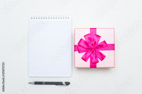 Notebook, gift box with pink ribbon and pen, copy space, top view