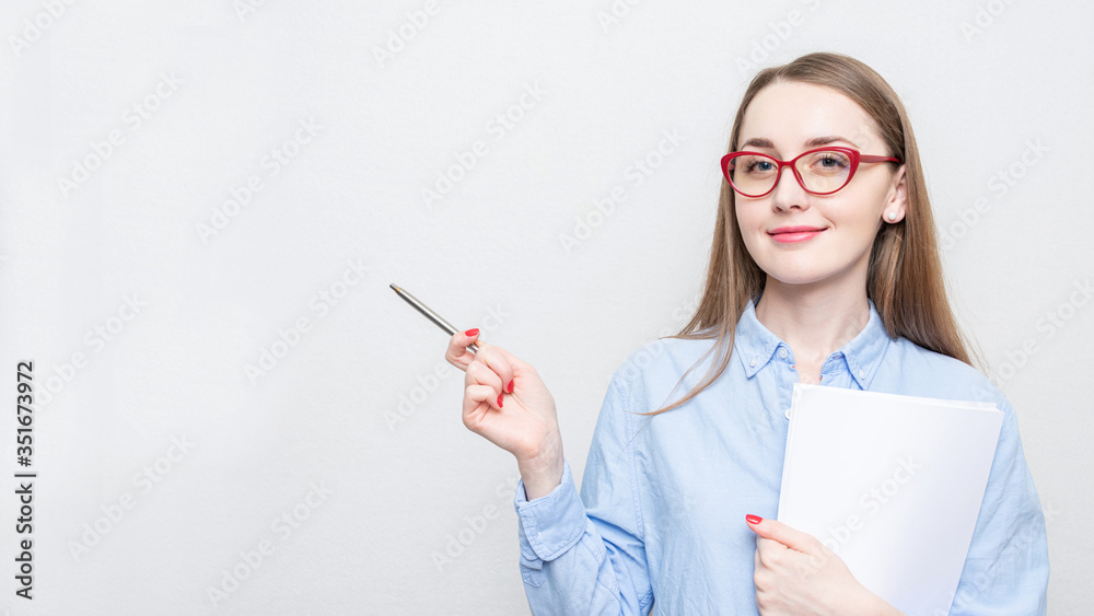 Pretty student in red glasses points to copy space, portrait, white background, copy space, 16:9