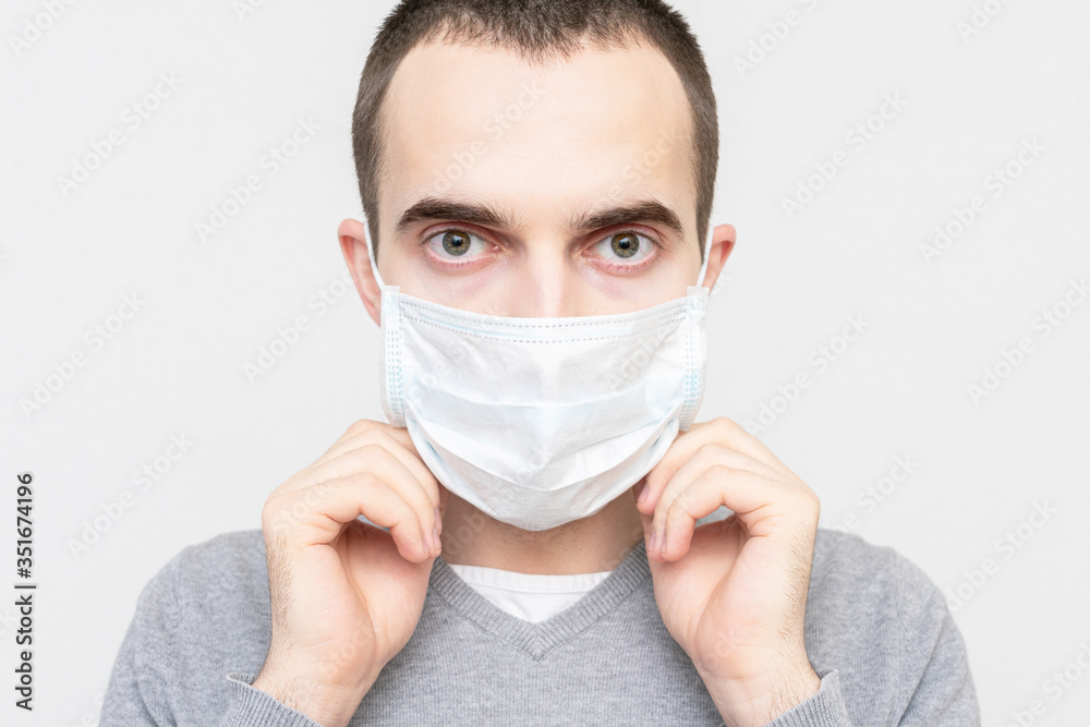 Man wears a medical mask, white background, portrait, closeup Man wears a medical mask, white background, portrait, closeup