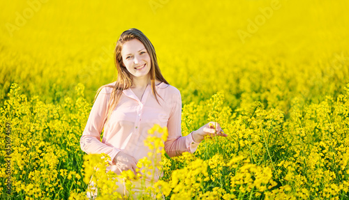 Girl in a blooming rapeseed field, cheerful happiness