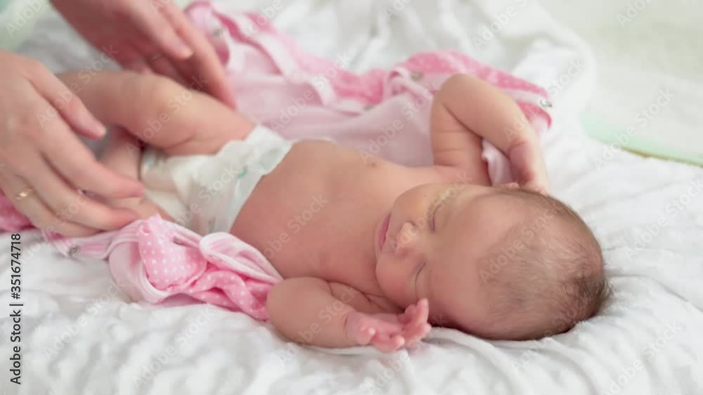 Cute little newborn baby girl sleeping in a dream. Mom gently takes the baby Cute little newborn baby girl sleeping in a dream. Mom gently takes the baby