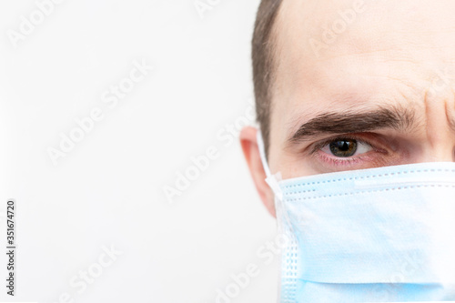 Man in medical face mask  guy has the flu  half face  portrait  closeup  white background  copy space