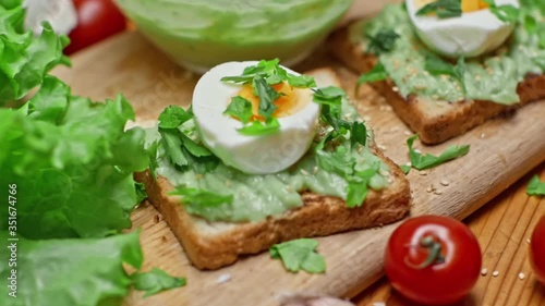 Toasts with avocado and guacamole with various fresh summer products on the table in slow motion. Cooking a delicious healthy vegetarian breakfast. Healthy eating and healthy lifestyle.