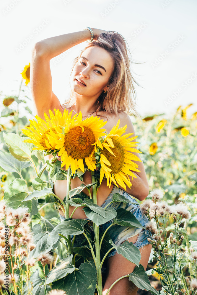 A young topless girl stands in sunflowers A young topless girl stands in sunflowers