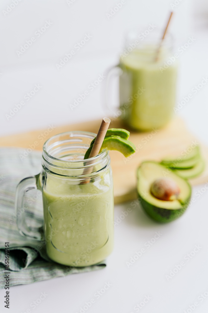 creamy smoothie from avocado and banana in glass cups with paper tubes on a light background. no plastic. healthy food creamy smoothie from avocado and banana in glass cups with paper tubes on a light background. no plastic. healthy food