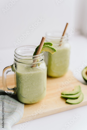creamy smoothie from avocado and banana in glass cups with paper tubes on a light background. no plastic. healthy food