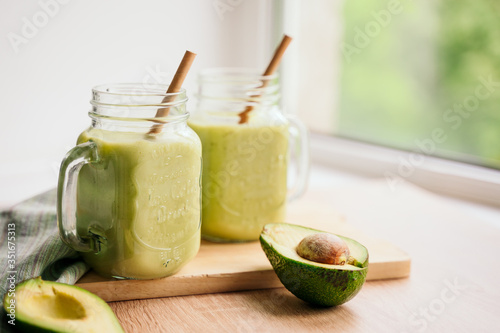 creamy smoothie from avocado and banana in glass cups with paper tubes on a light background. no plastic. healthy food