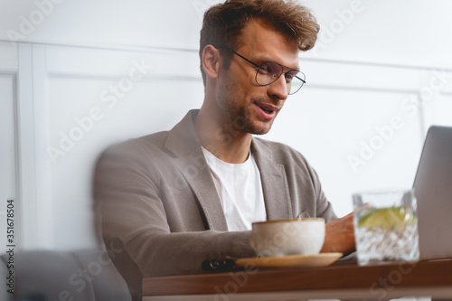 Good-looking gentleman using modern laptop in cafe