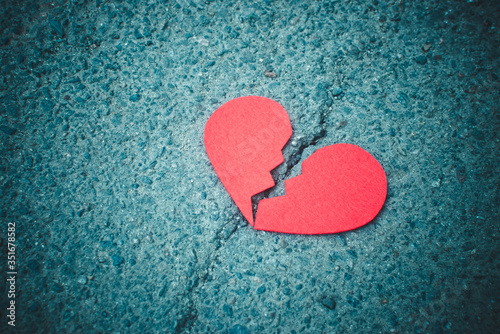 Red broken heart on asphalt background - dark and moody