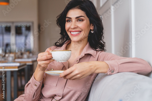 Charming young woman drinking hot beverage in cafe