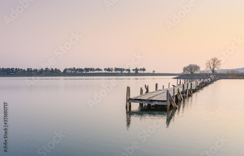 Early morning. Smooth surface of the lake and the old wooden bridge destroyed Place for relaxation and meditation. Place for fishing. © Kate