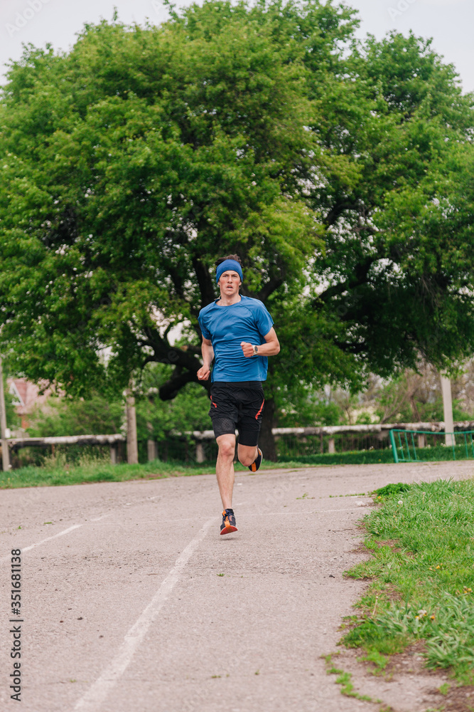 A young athlete in a blue T-shirt runs around the stadium A young athlete in a blue T-shirt runs around the stadium