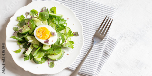 Fresh cucumber salad with micro greens and egg. Trending food. Top view, flat layout, copy space