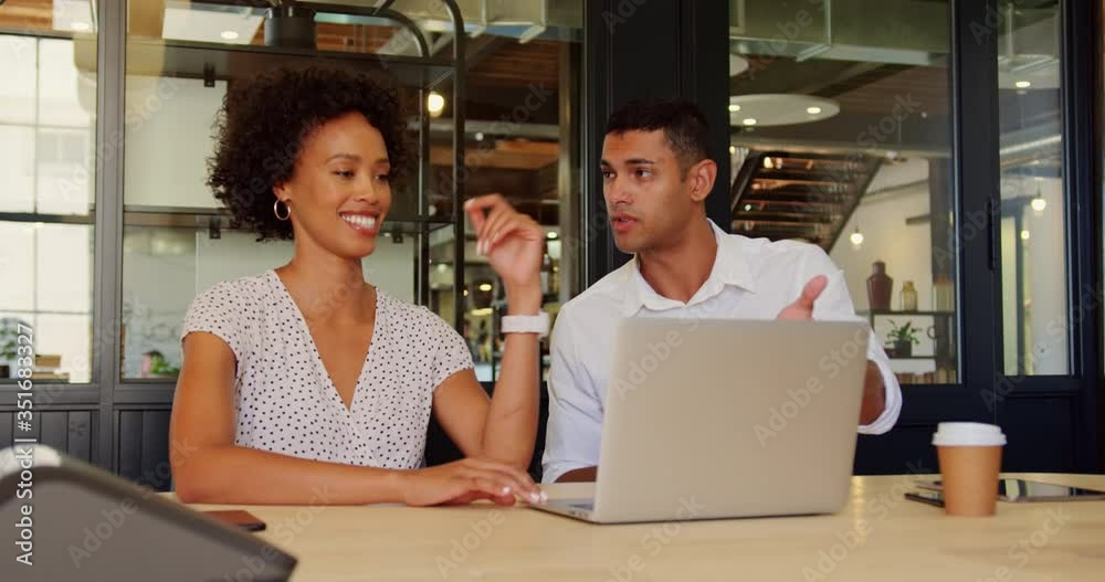 Business people discussing over laptop in modern office