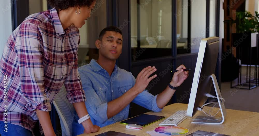 Graphic designers discussing over computer in a modern office