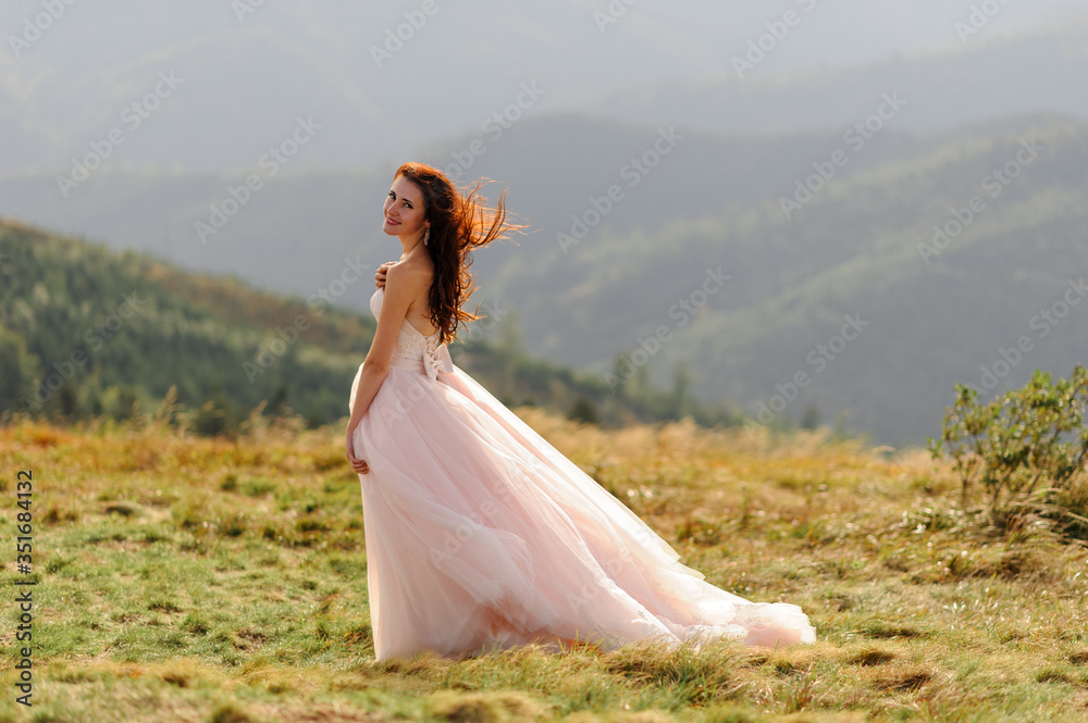 Portrait of a beautiful bride on a background of autumn mountains. The wind blows her hair. Wedding ceremony on top of the mountain. Free space.