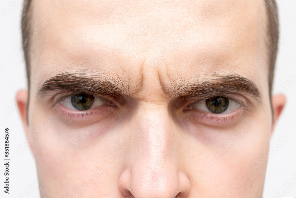 Fototapeta premium Face of gloomy man, man's eyes, cropped image, closeup, white background
