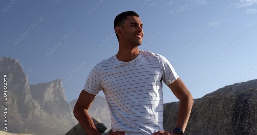 Man with hands on hip and arms crossed standing on beach