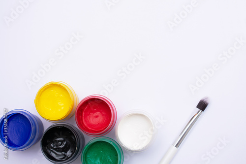 Bottle of different colors gouache paints and artist brush, white background, copy space, top view