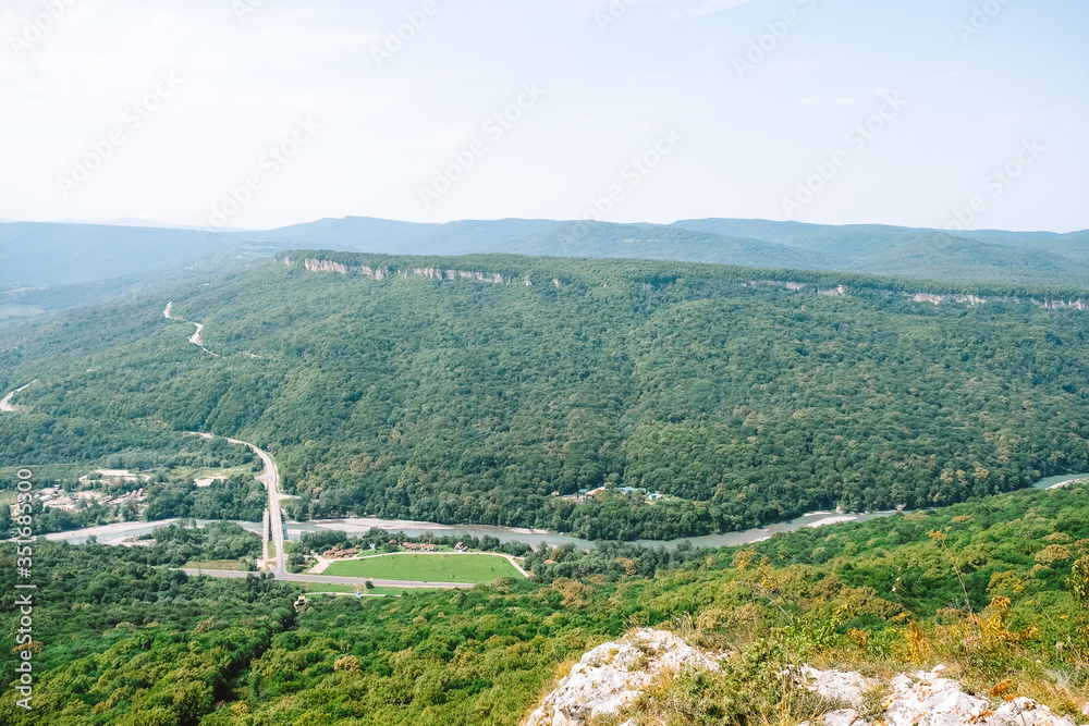view from a cliff to a mountain village below on a summer sunny day green forest a secluded place