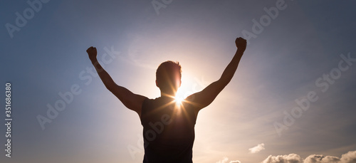 Victorious man with strong arms up in the sunset sky. People power and hope. 