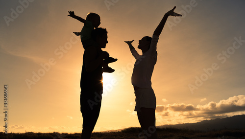 Happy family silhouette with arms up in the air at sunset. 