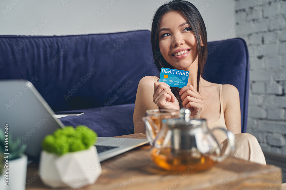Attractive young woman holding debit card and smiling Attractive young woman holding debit card and smiling