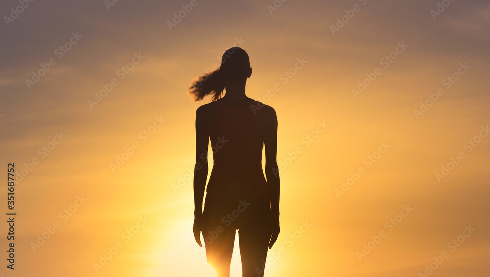 Silhouette of woman's standing in the sunset sky. 